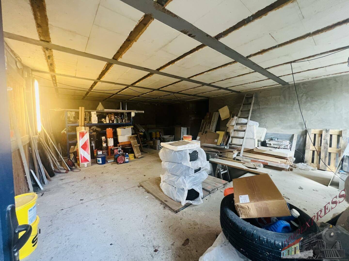 Großer Lagerraum mit verschiedenen Gegenständen, Paletten und Baumaterialien.