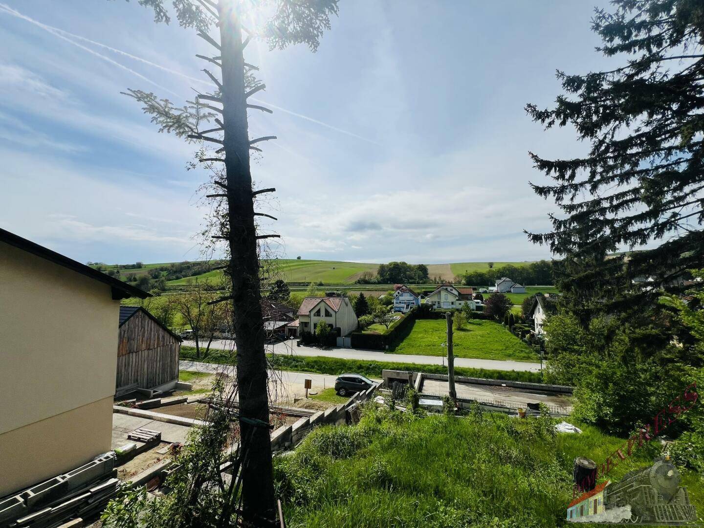 Blick über eine Baustelle auf die weite, grüne Landschaft mit Häusern in der Ferne.