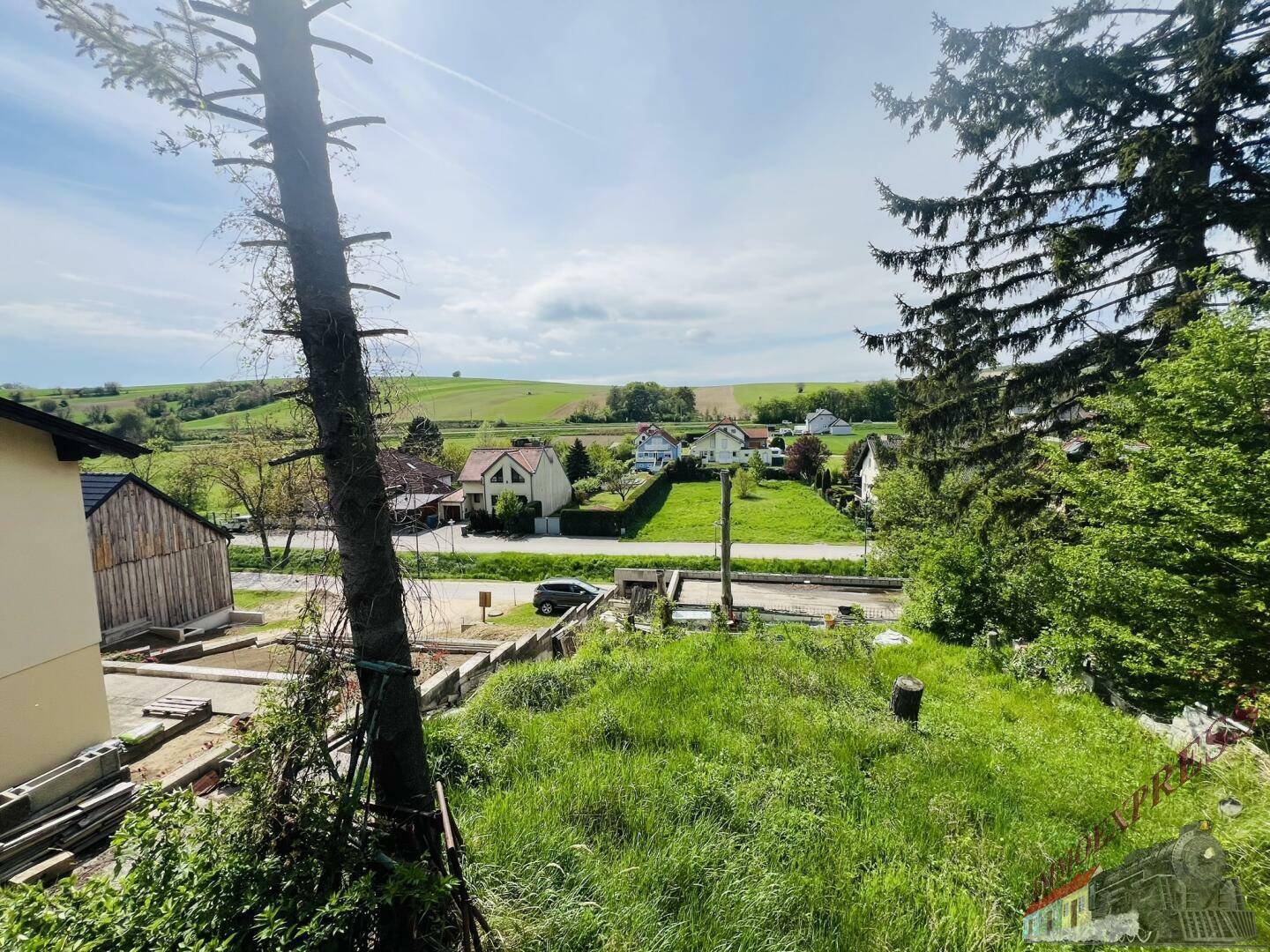 Panoramablick auf die ländliche Umgebung mit Feldern und vereinzelten Gebäuden unter hellem Himmel.