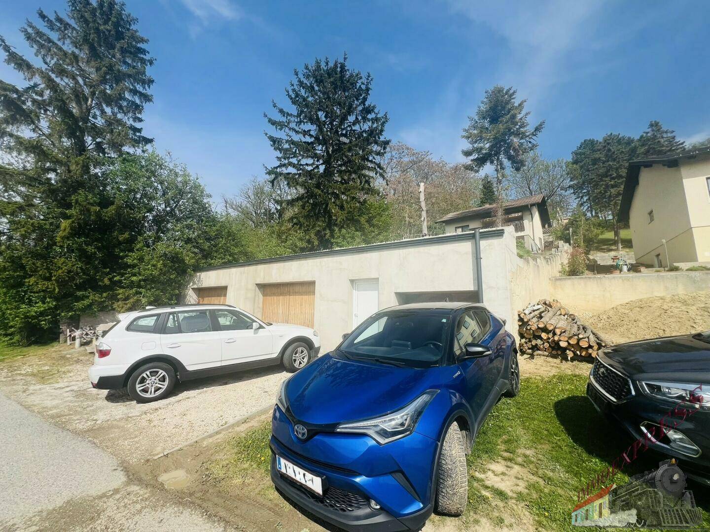 Garagengebäude mit zwei Toren und Stellplätzen für Fahrzeuge im Freien.