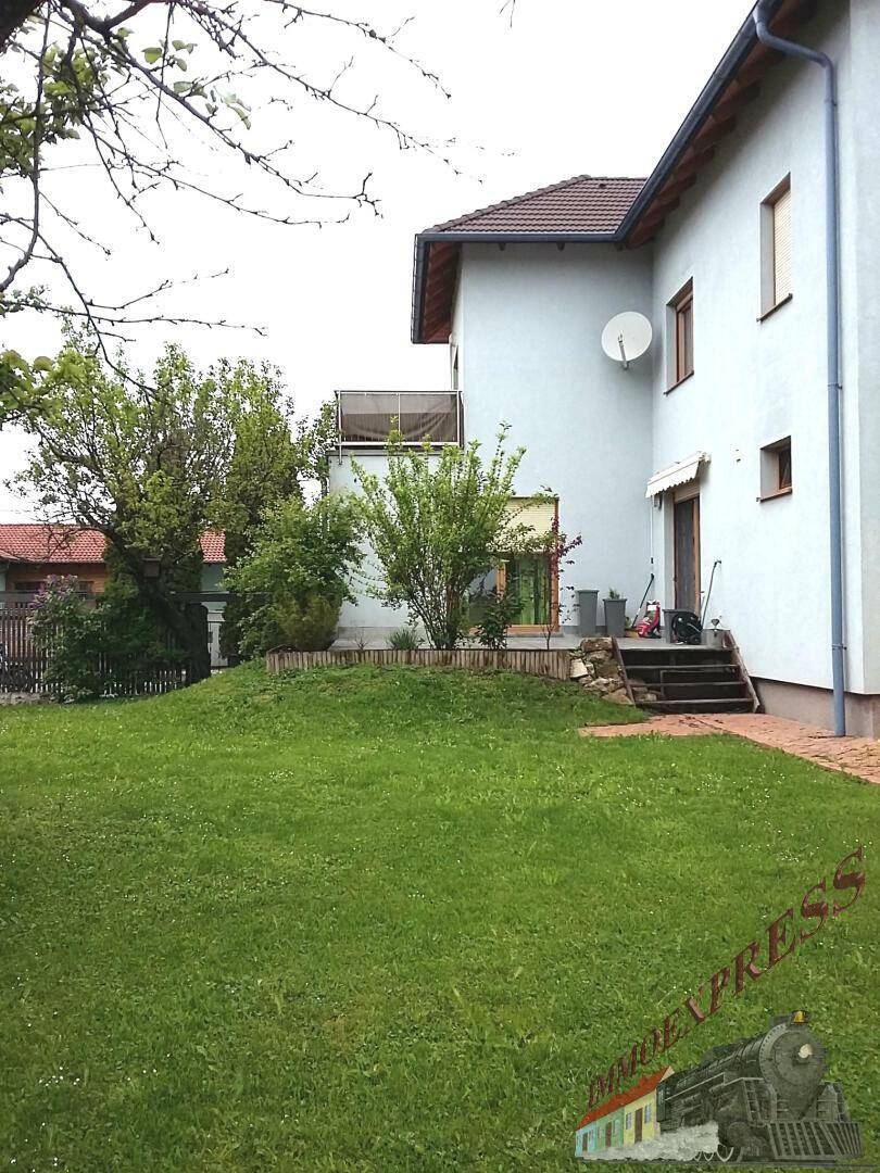Seitenansicht des Hauses mit großem Garten, Rasenfläche und Zugang zur Terrasse.