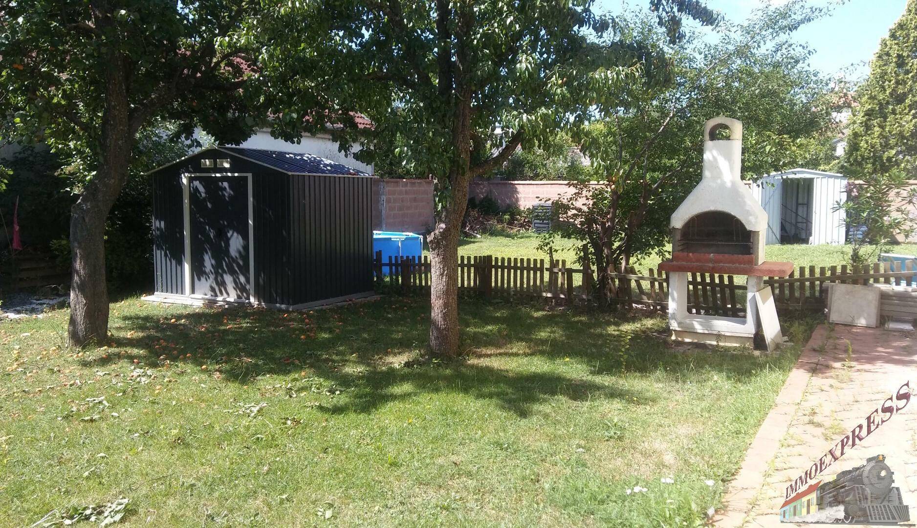Sonniger Gartenbereich mit Rasen, Gartenhaus und gemauertem Grillplatz für gesellige Stunden.