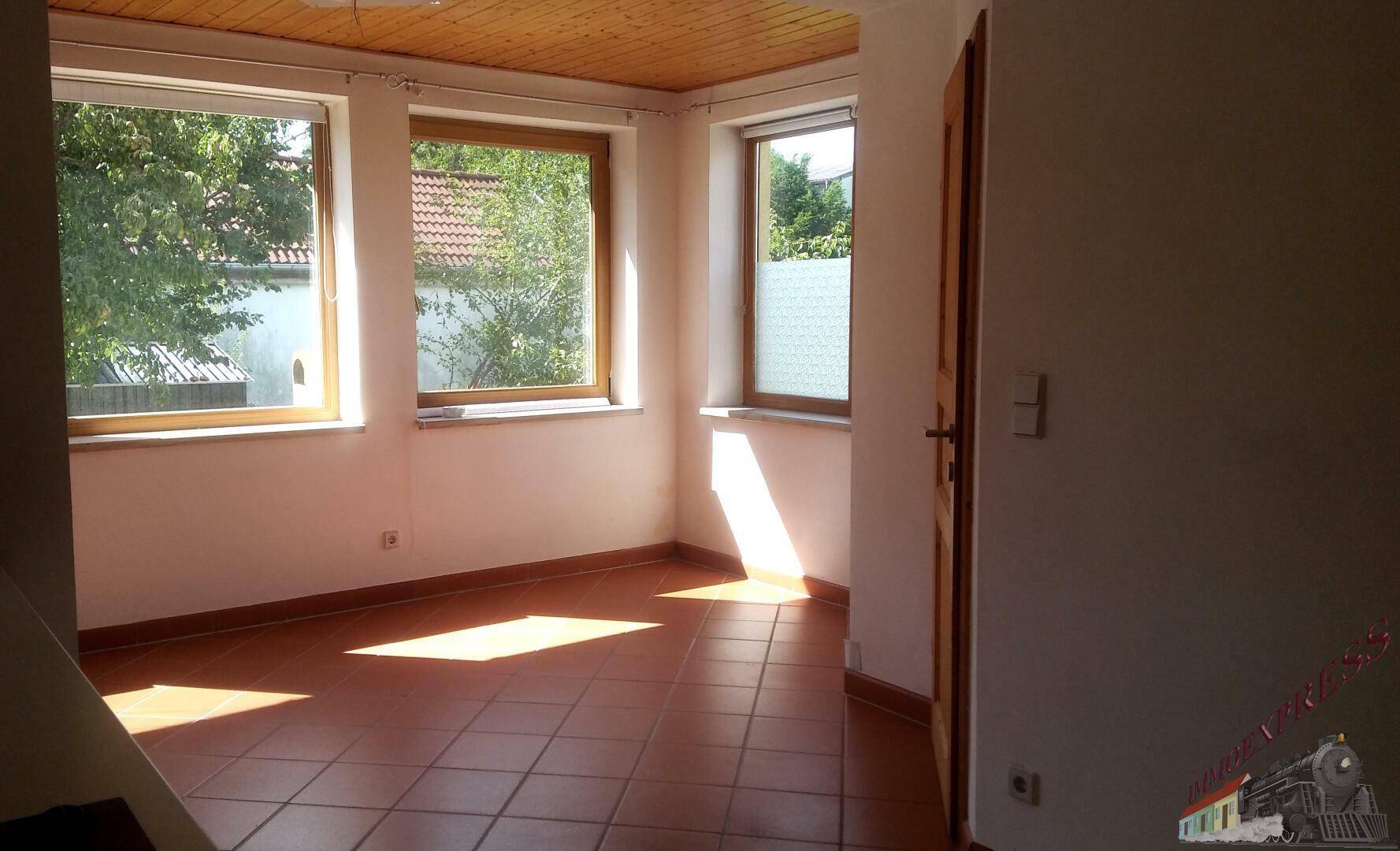 Heller Raum mit Terrakottafliesen, Holzdecke und mehreren Fenstern für viel Tageslicht.