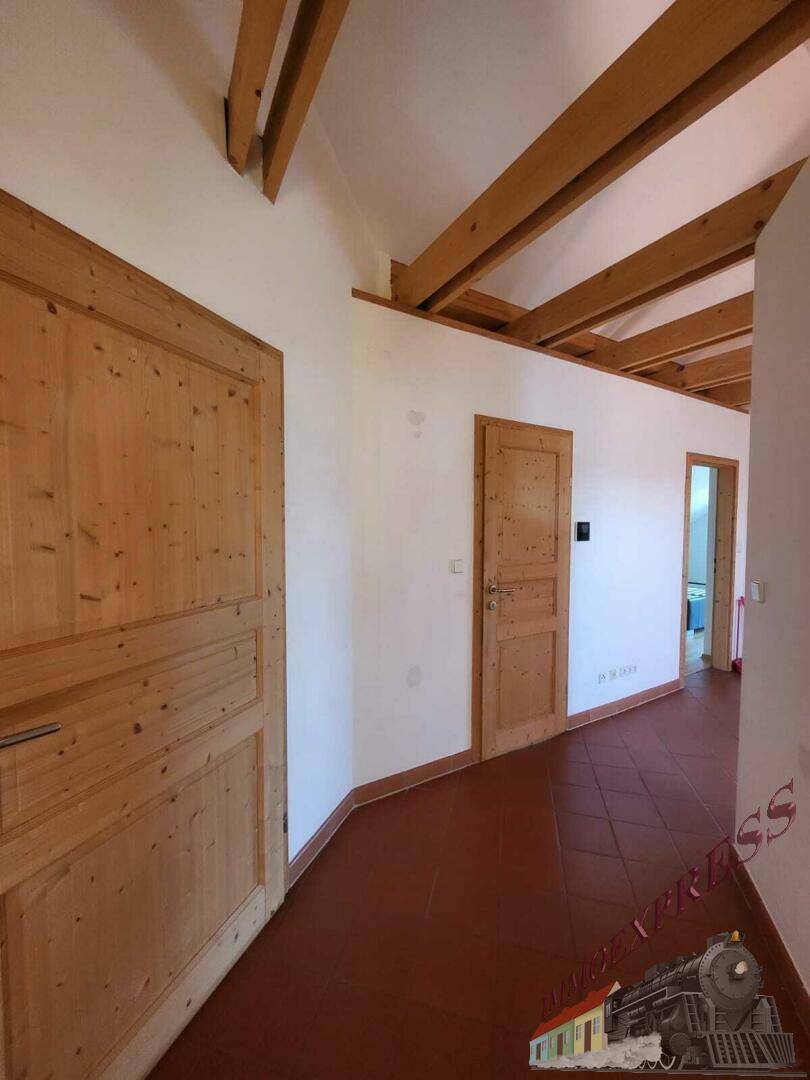 Flur mit rustikalen Holztüren, Terrakottafliesen und sichtbaren Holzbalken an der Decke.