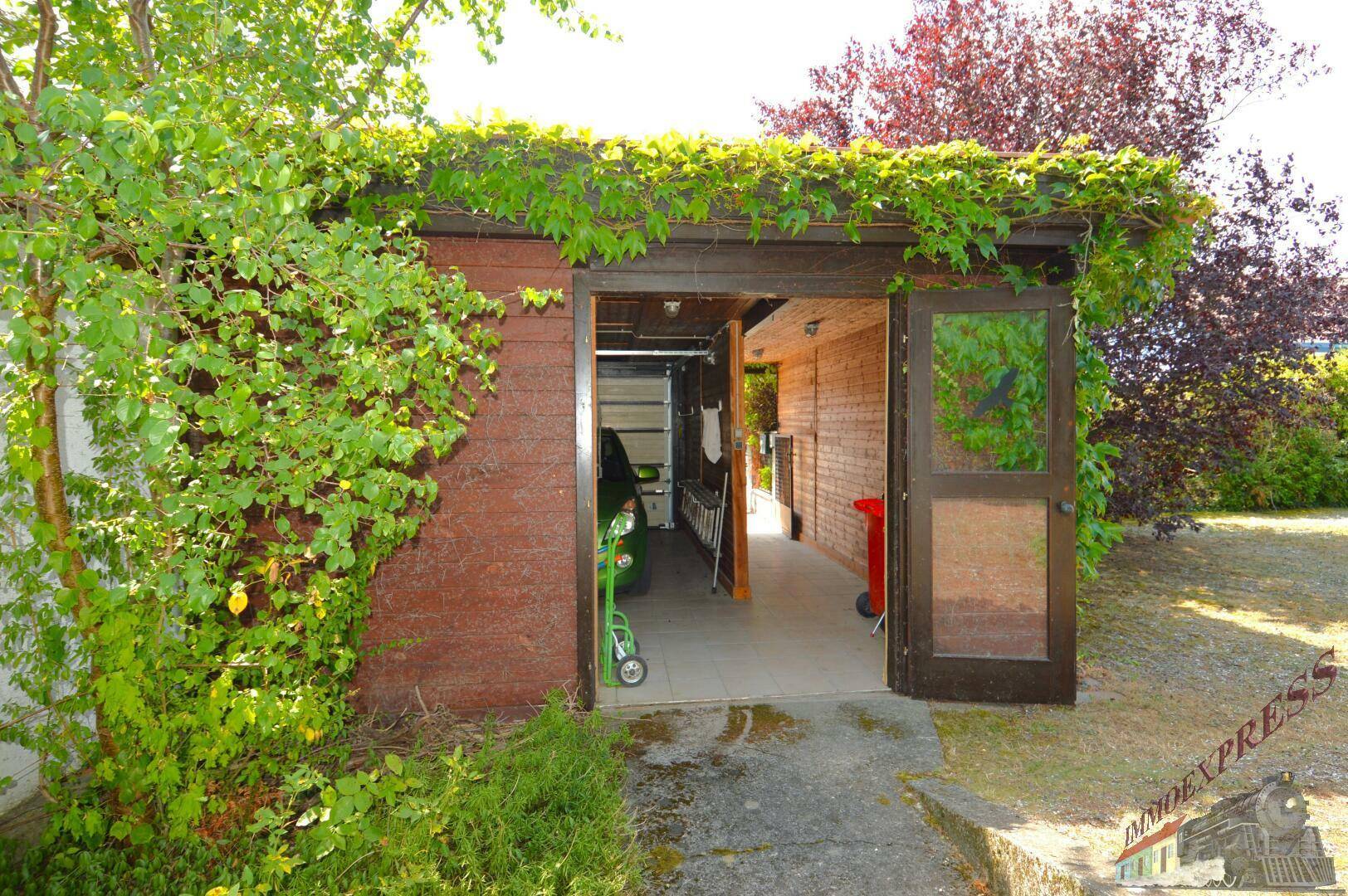 Überdachter Garagenbereich mit begrüntem Dach und Zugang zum Grundstück.