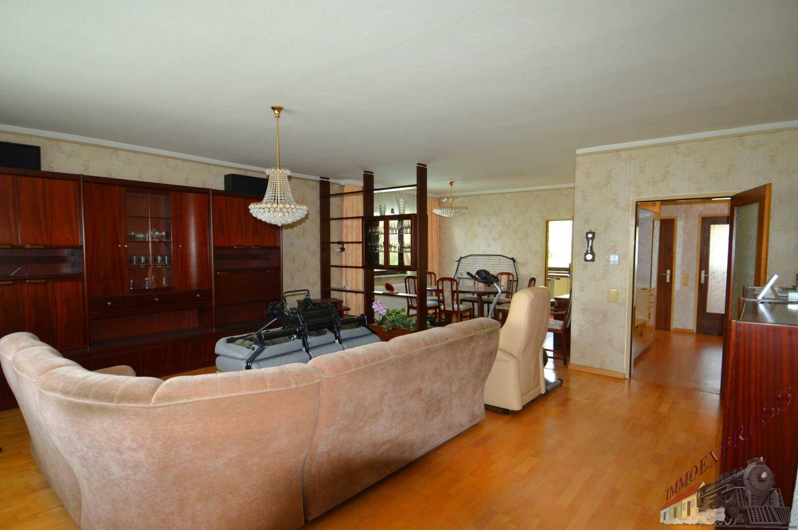 Offener Wohnbereich mit Parkettboden, großem Sofa und Blick auf den Essbereich.