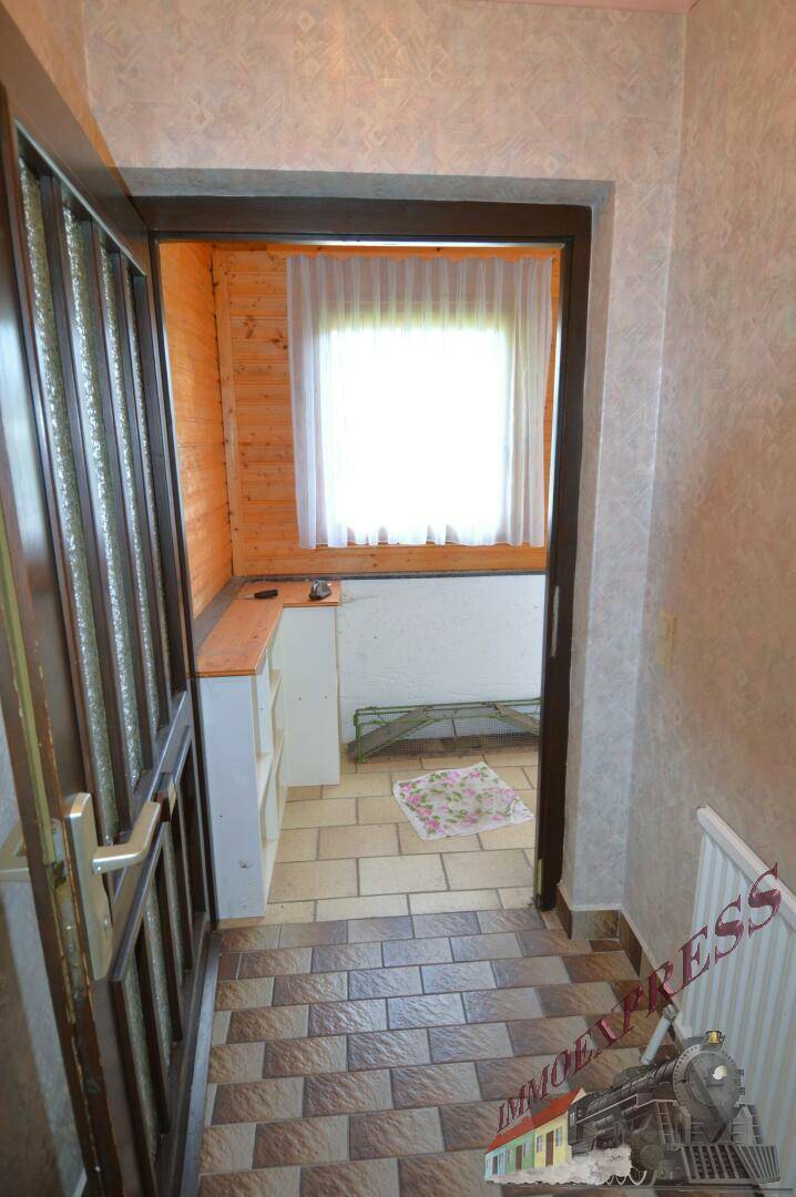 Eingangsbereich mit gefliestem Boden, Holzvertäfelung und Fenster mit Vorhängen.