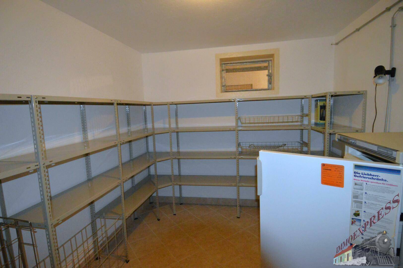 Geräumiger Lagerraum im Keller mit umfangreichen Regalsystemen und Gefrierschrank.