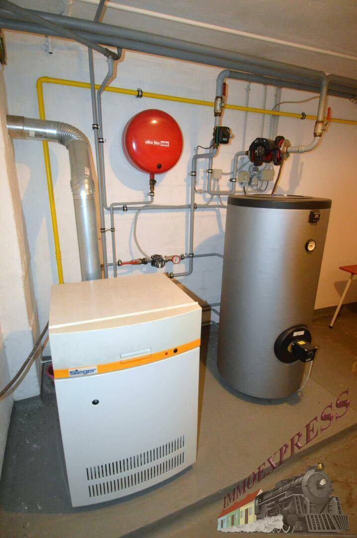Detailansicht der Heizungsanlage und des Warmwasserspeichers im Keller.