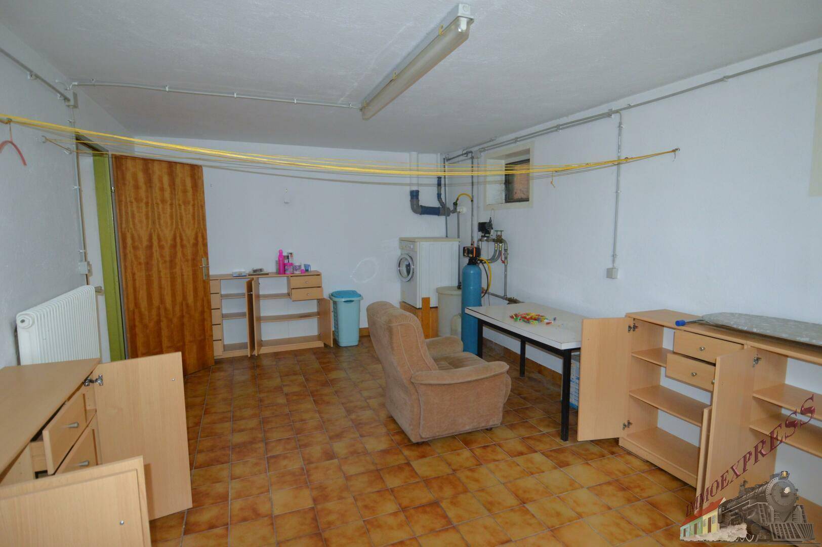 Hauswirtschaftsraum im Keller mit Waschmaschine, Arbeitsflächen und Stauraum.