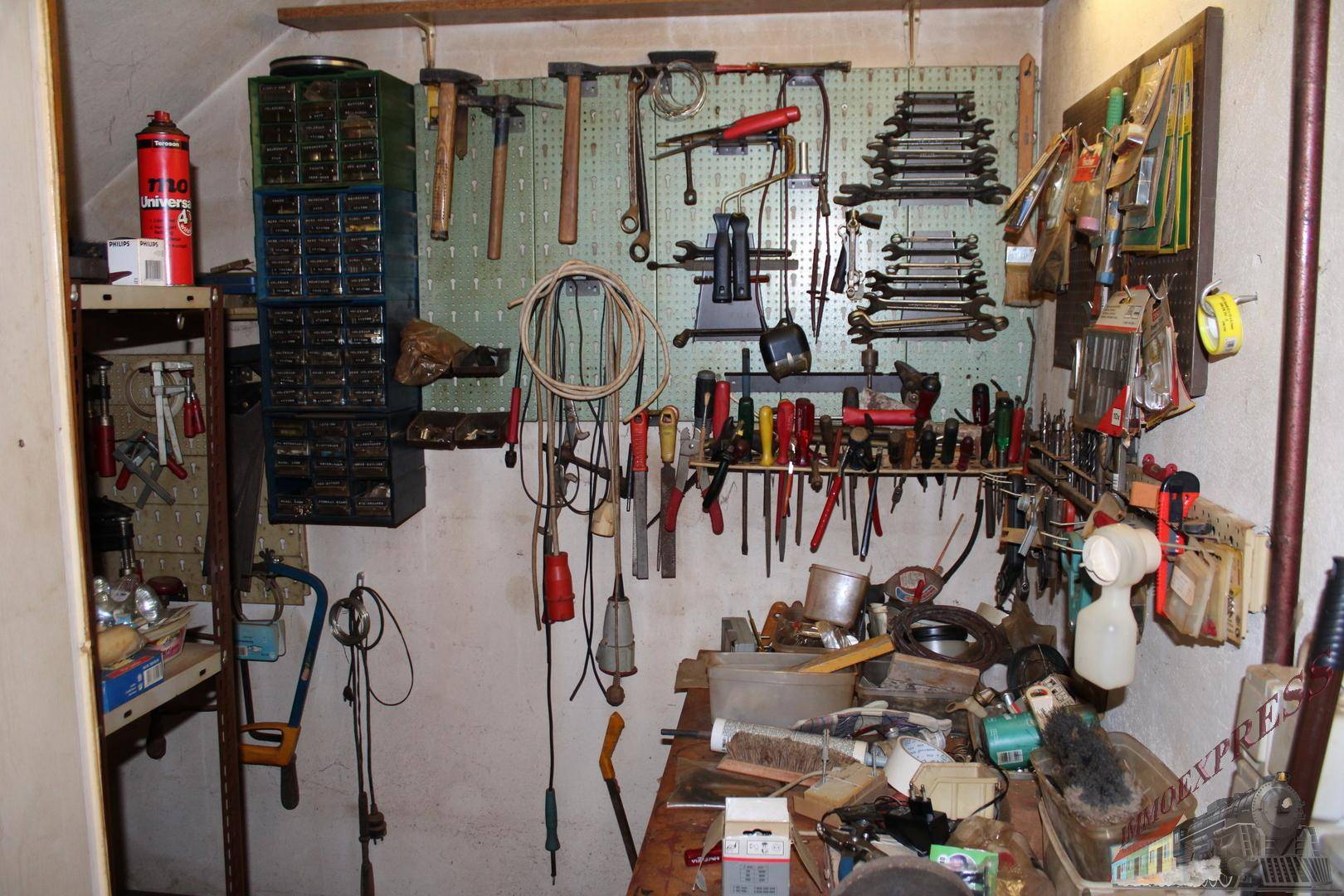 Werkstattraum mit Werkbank und einer Vielzahl von Werkzeugen an der Wand.
