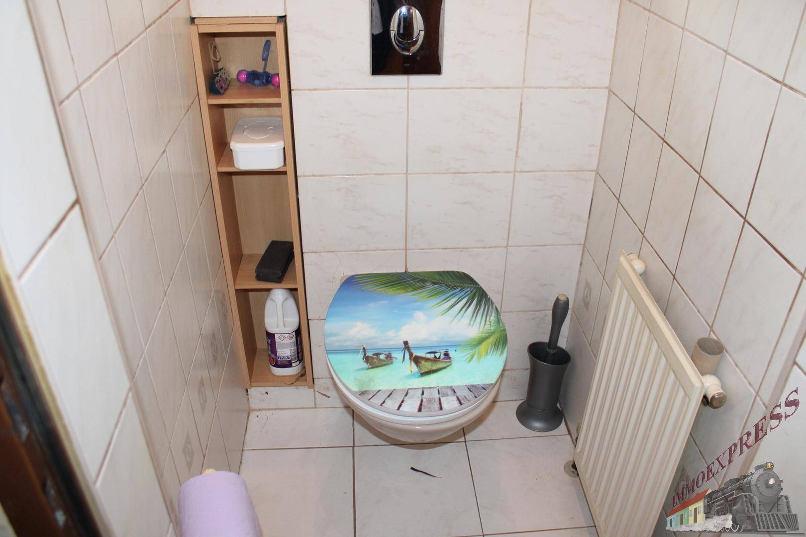Separate Toilette mit Fliesen an Wänden und Boden sowie einem Heizkörper.