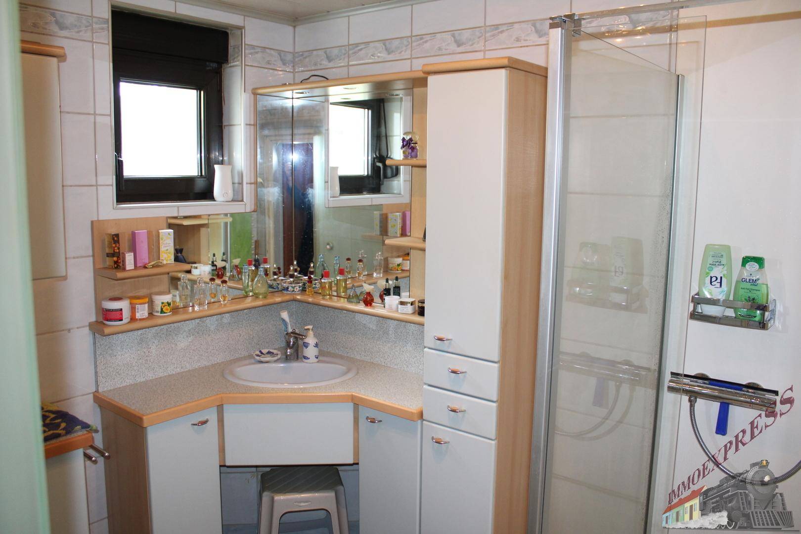 Badezimmer mit Dusche, Eckwaschbecken und Spiegelschrank.