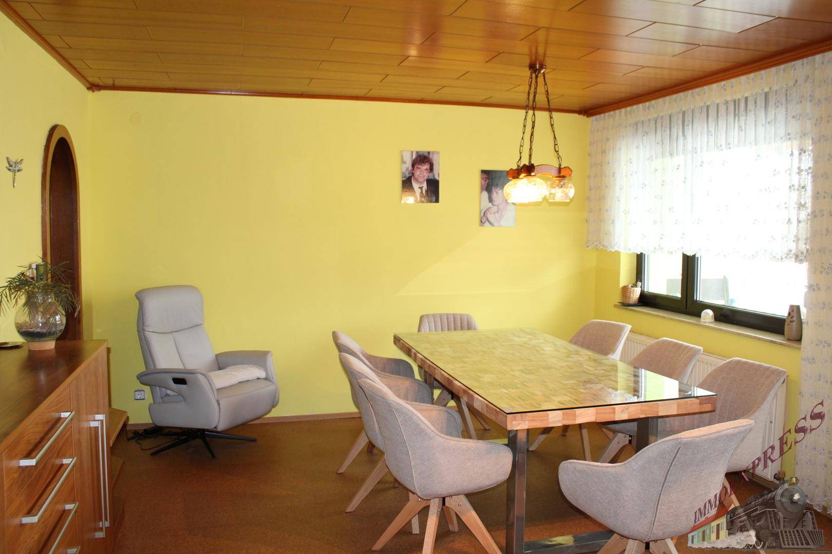 Gemütlicher Essbereich mit Holztäfelung an der Decke, gelben Wänden und einem großen Esstisch.