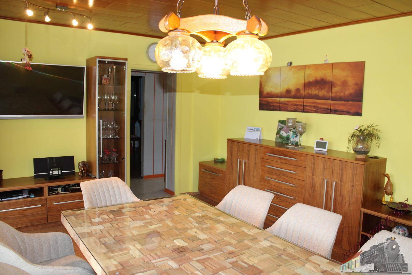 Esszimmer mit Holztisch, passenden Stühlen und einem Sideboard aus Holz.