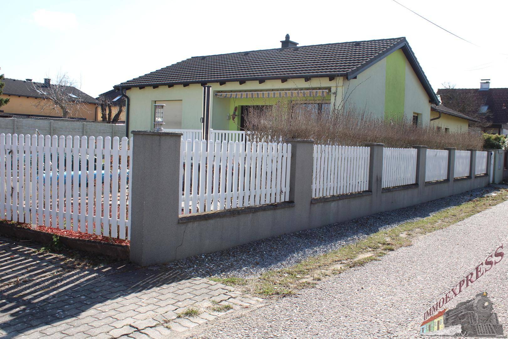 Vorderansicht des Hauses mit weißem Lattenzaun und gepflegtem Vorgartenbereich.