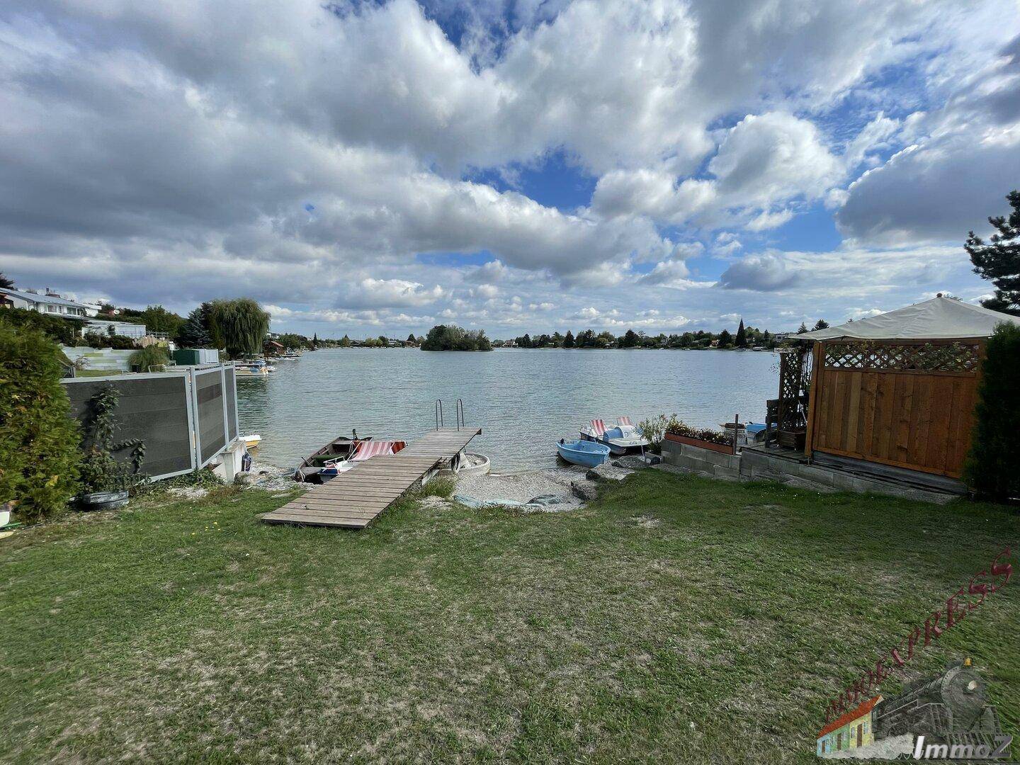 Gartenbereich mit direktem Zugang zu einem See, Steg und einem kleinen Pavillon.