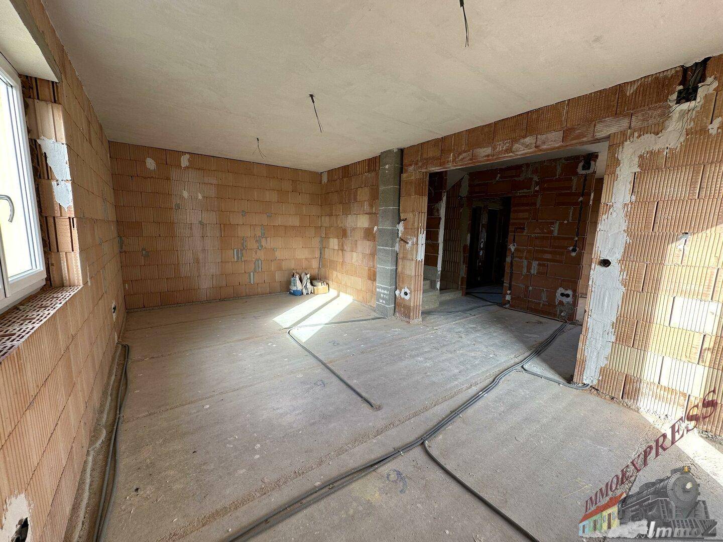 Geräumiger Rohbau mit Ziegelwänden, Estrichboden und vorbereiteten Installationen.