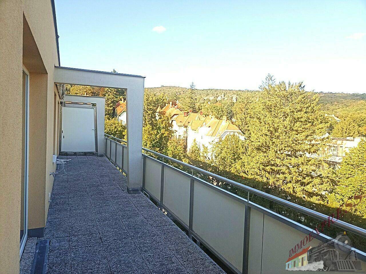 Großer Balkon mit Panoramablick über eine grüne Landschaft und entfernte Gebäude.