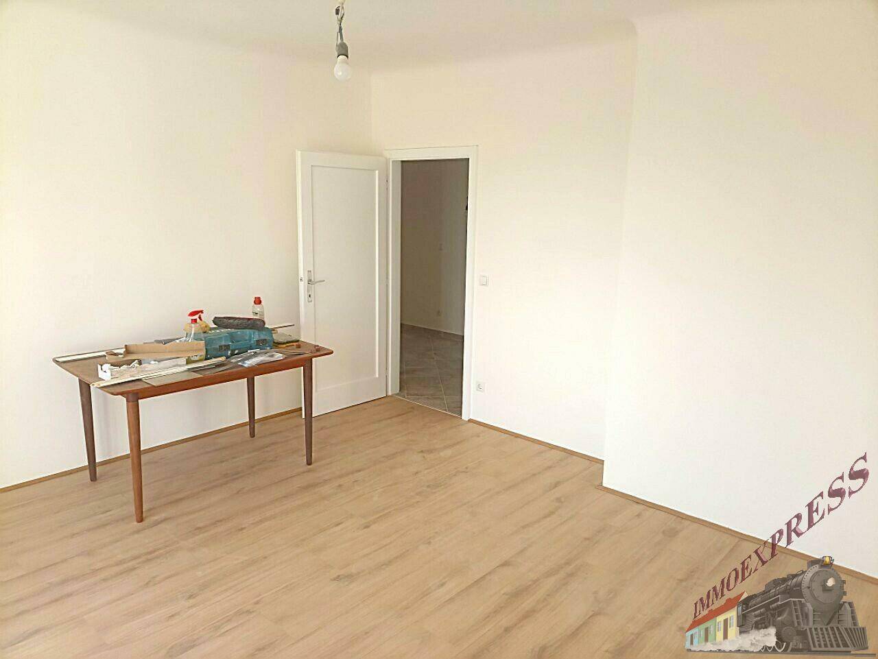 Leerer Wohnraum mit Holzboden und weiß gestrichenen Wänden, ideal für individuelle Gestaltung.