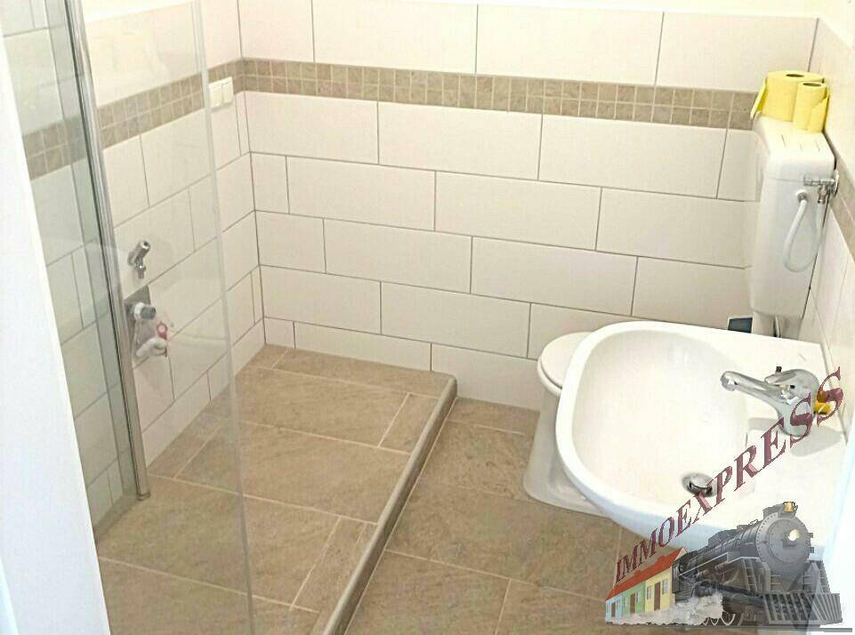Modernes Badezimmer mit Dusche, WC und Bidet, gefliest in Weiß und Beige.