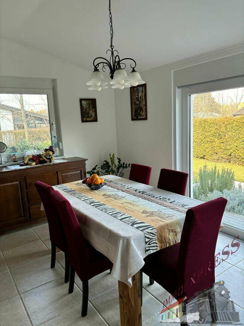 Heller Essbereich mit Holztisch, roten Stühlen, Fliesenboden und Blick in den Garten.