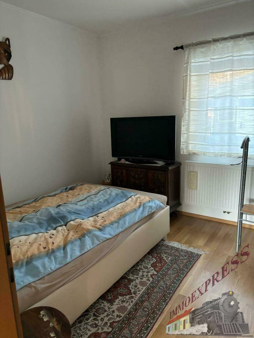 Gemütliches Schlafzimmer mit Einzelbett, Holzfußboden und Fernseher auf einer Kommode.