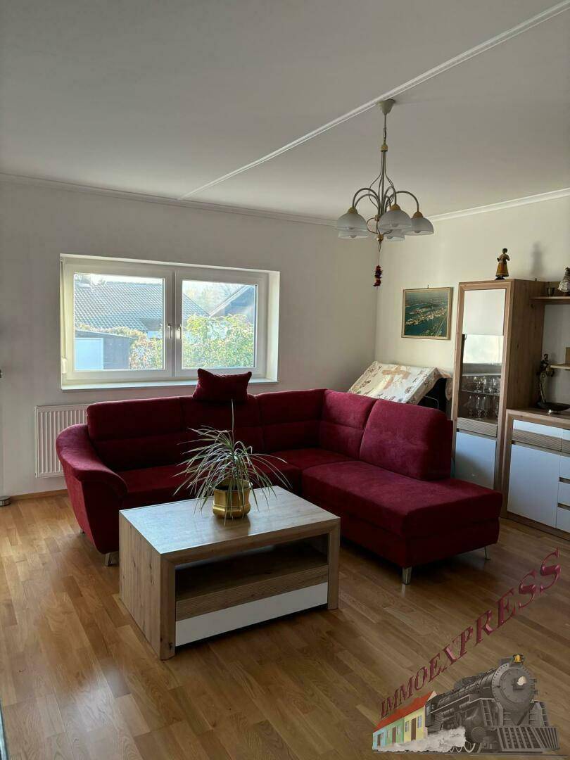 Helles Wohnzimmer mit rotem Ecksofa, Couchtisch und Holzfußboden.