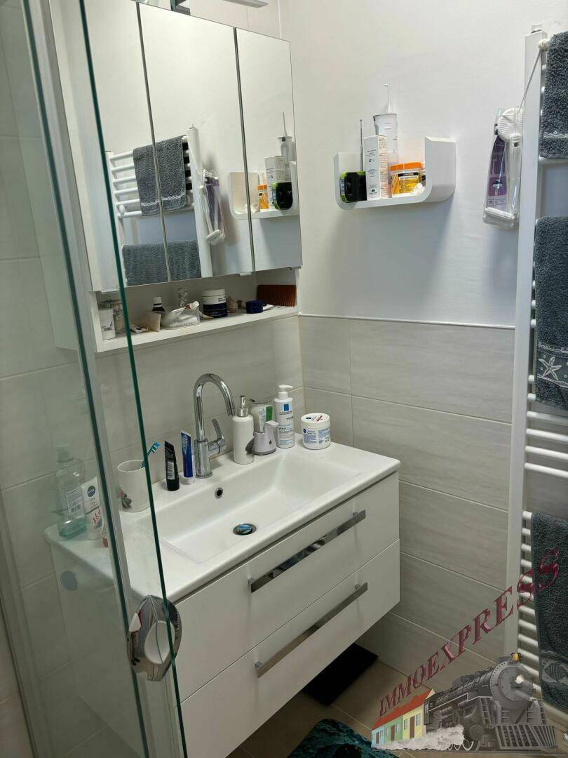 Modernes Badezimmer mit Waschtisch, Spiegelschrank und beheiztem Handtuchhalter.