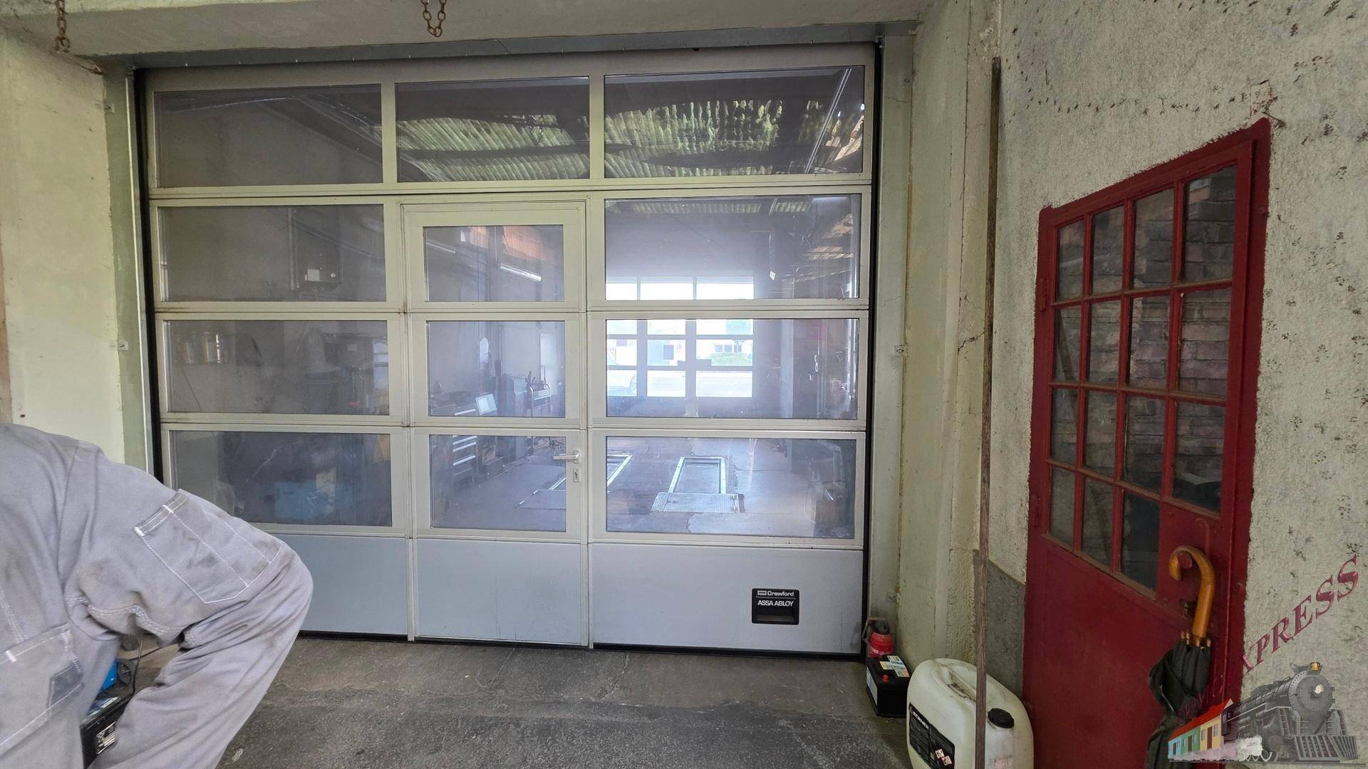 Große Glas-Sektionaltür in einer Werkstatt oder Garage mit einer roten Nebentür.