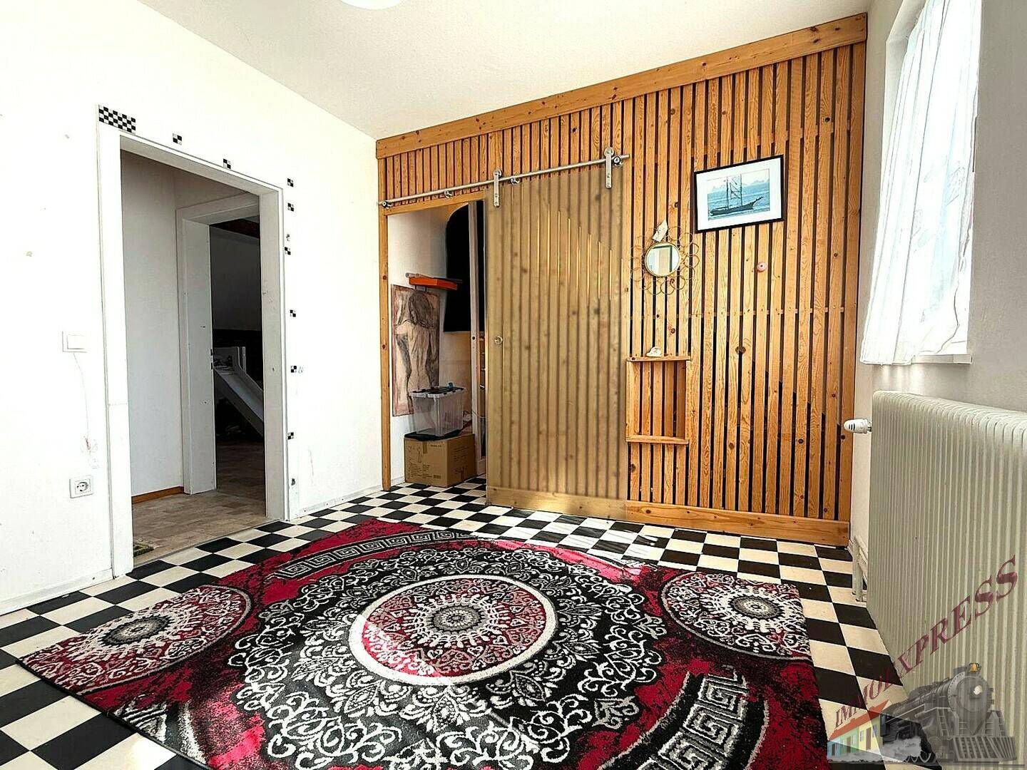 Raum mit auffälligem Schachbrettmuster-Boden, Holzwandverkleidung und Schiebetür.