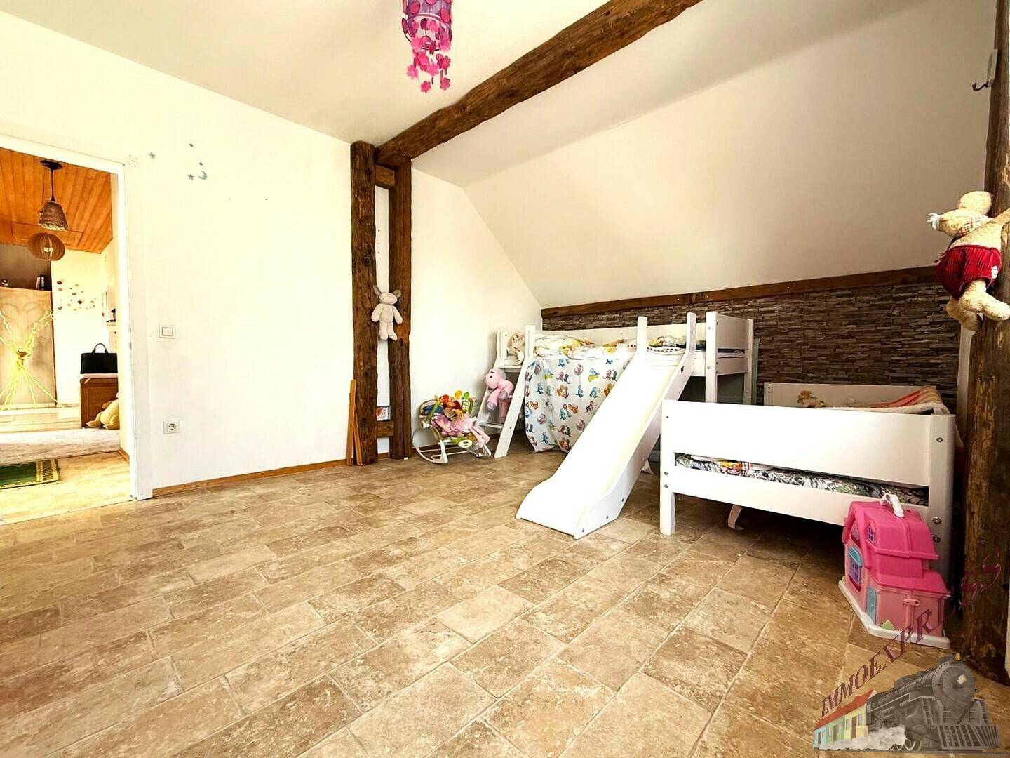 Kinderzimmer mit Dachschräge, Holzbalken und Etagenbett, hell und freundlich gestaltet.