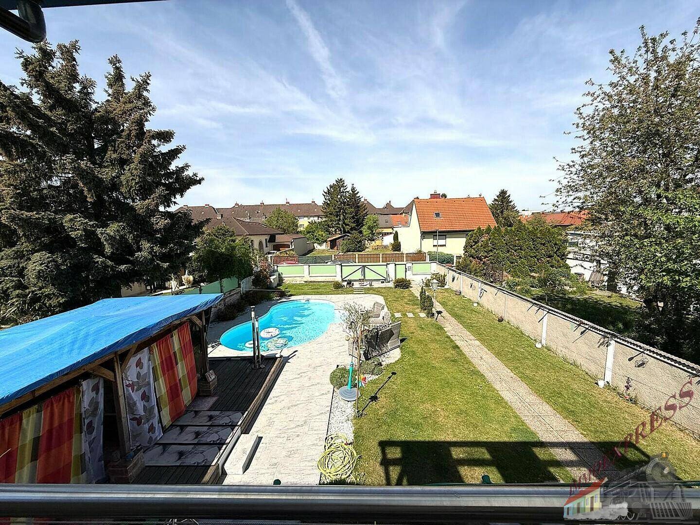 Weitläufiger Gartenbereich mit großem Pool, Rasenflächen und überdachtem Sitzbereich von oben.