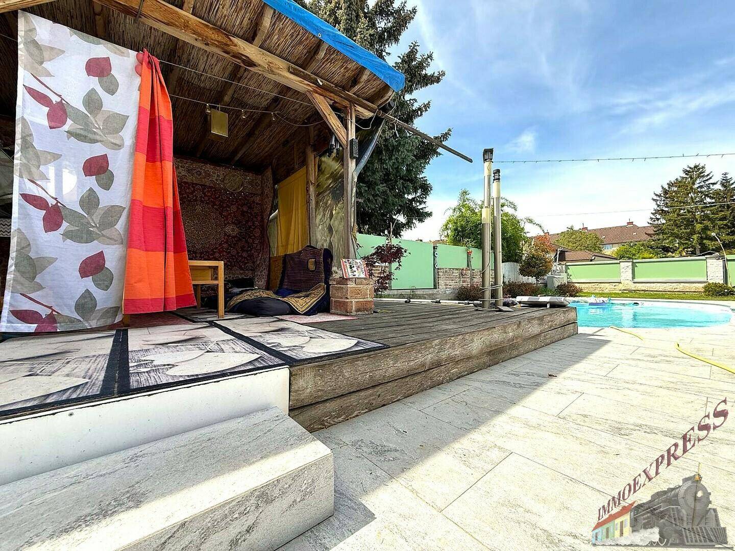Überdachter Außenbereich mit Holzboden und Blick auf den Pool, ideal zum Entspannen.