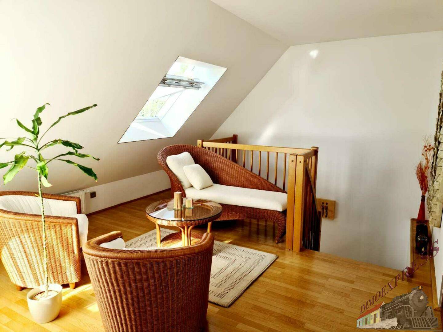 Gemütlicher Wohnbereich mit Dachschrägen, einem Dachfenster und rustikalen Korbmöbeln auf Holzfußboden.