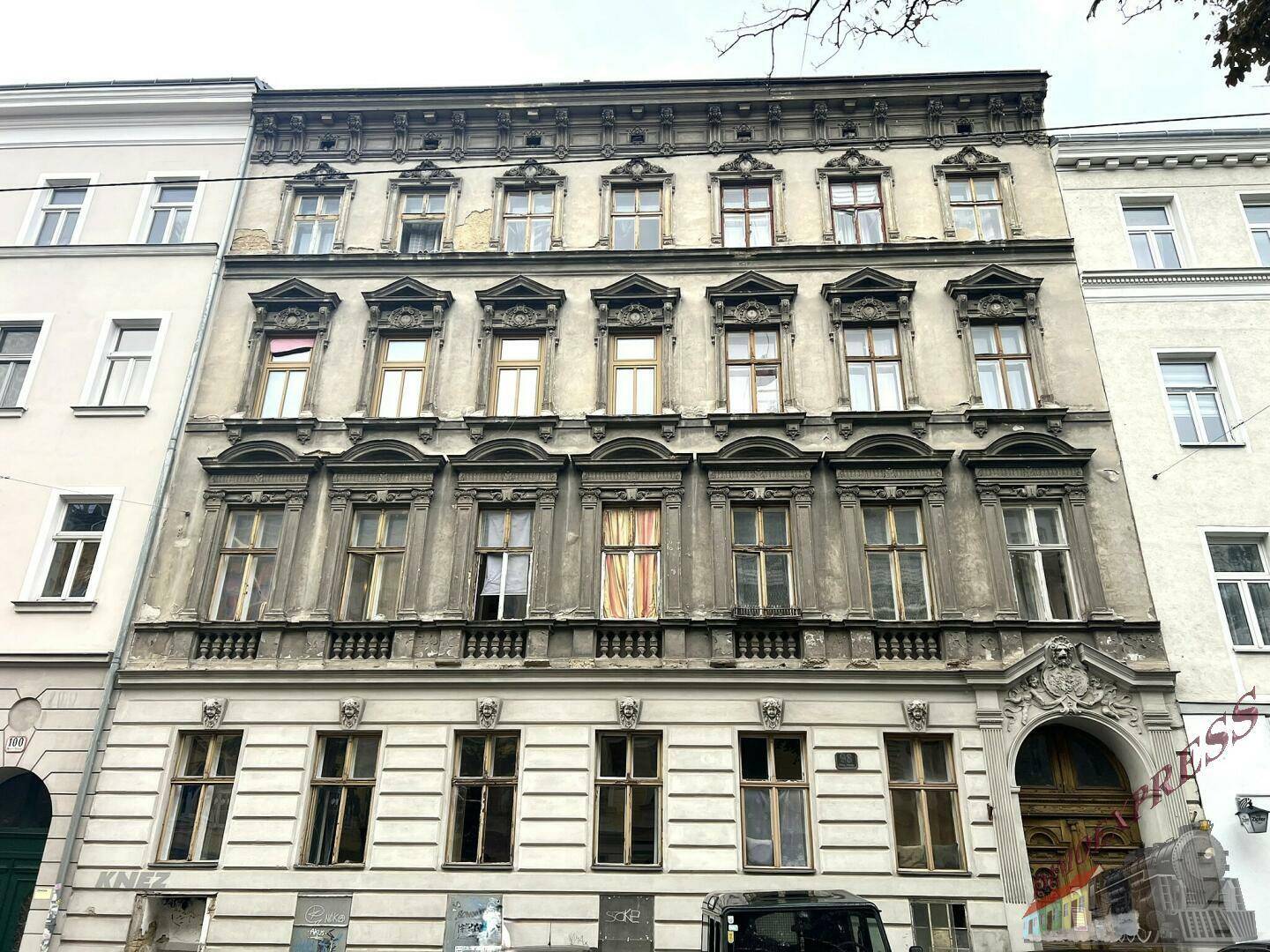 Historische Gebäudefassade mit aufwendigen Verzierungen und vielen Fenstern in einer städtischen Umgebung.