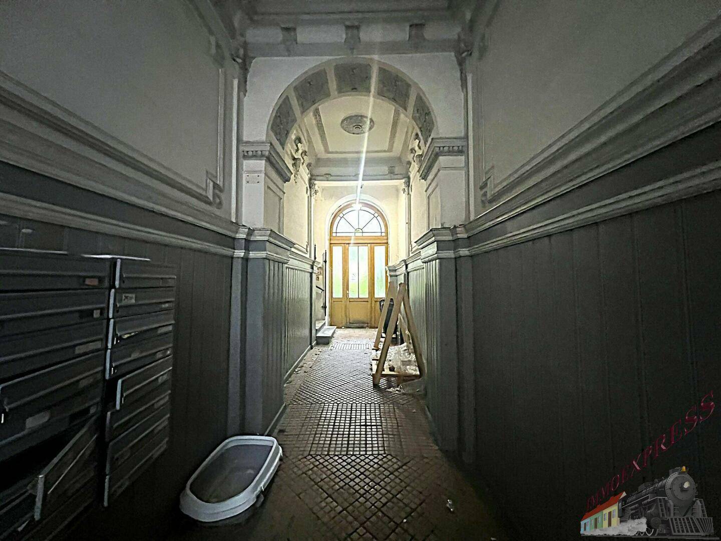 Langer, historischer Flur mit gewölbter Decke, Stuckverzierungen und Briefkästen im Eingangsbereich.