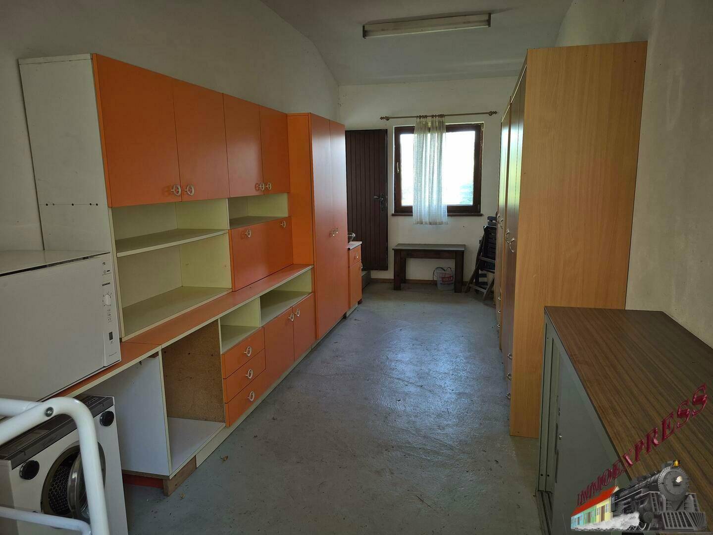 Großer Hauswirtschaftsraum mit Schränken, Waschmaschine und Fenster.