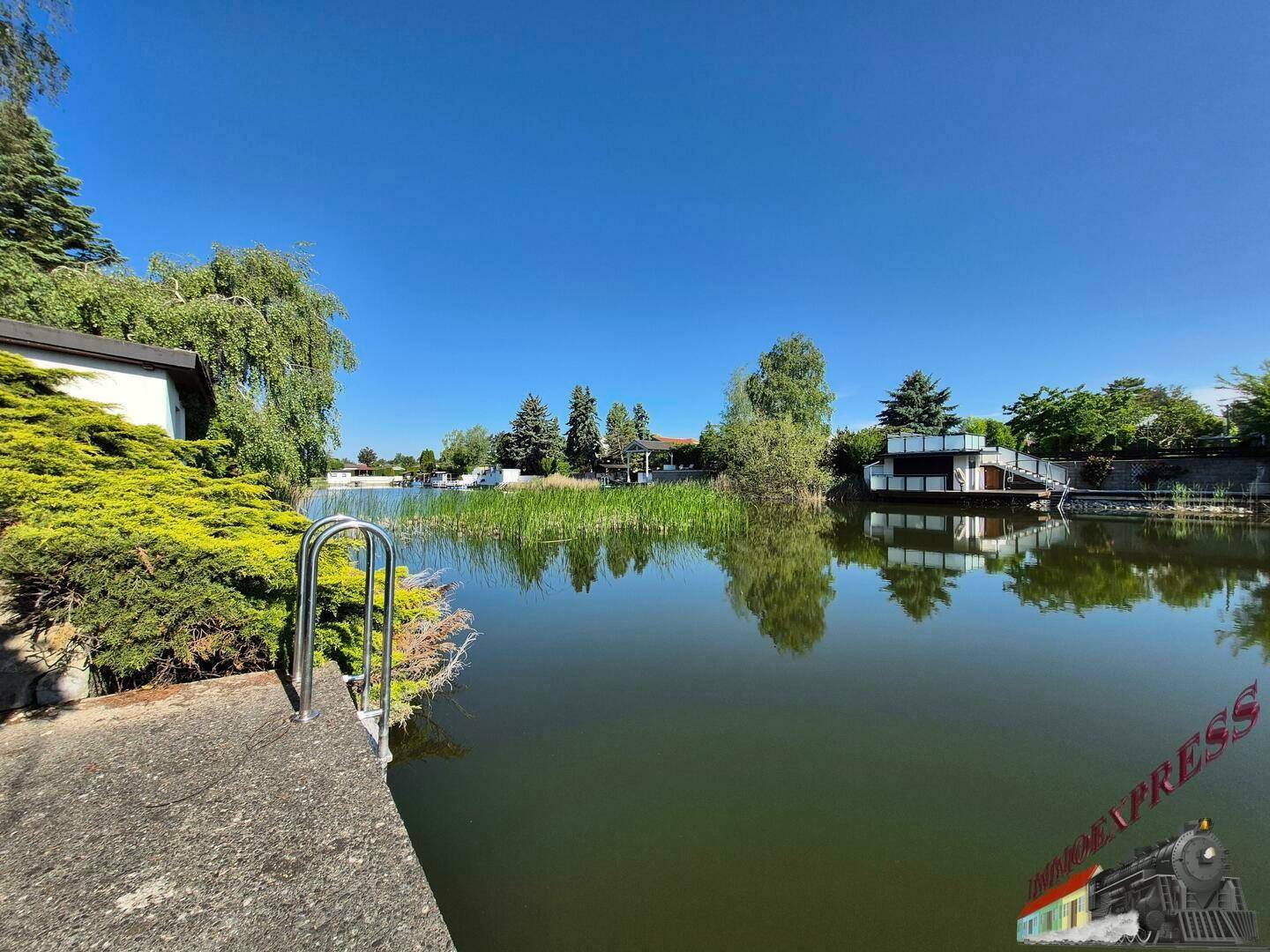 Panoramablick auf den See mit Badestelle und umliegender Natur.