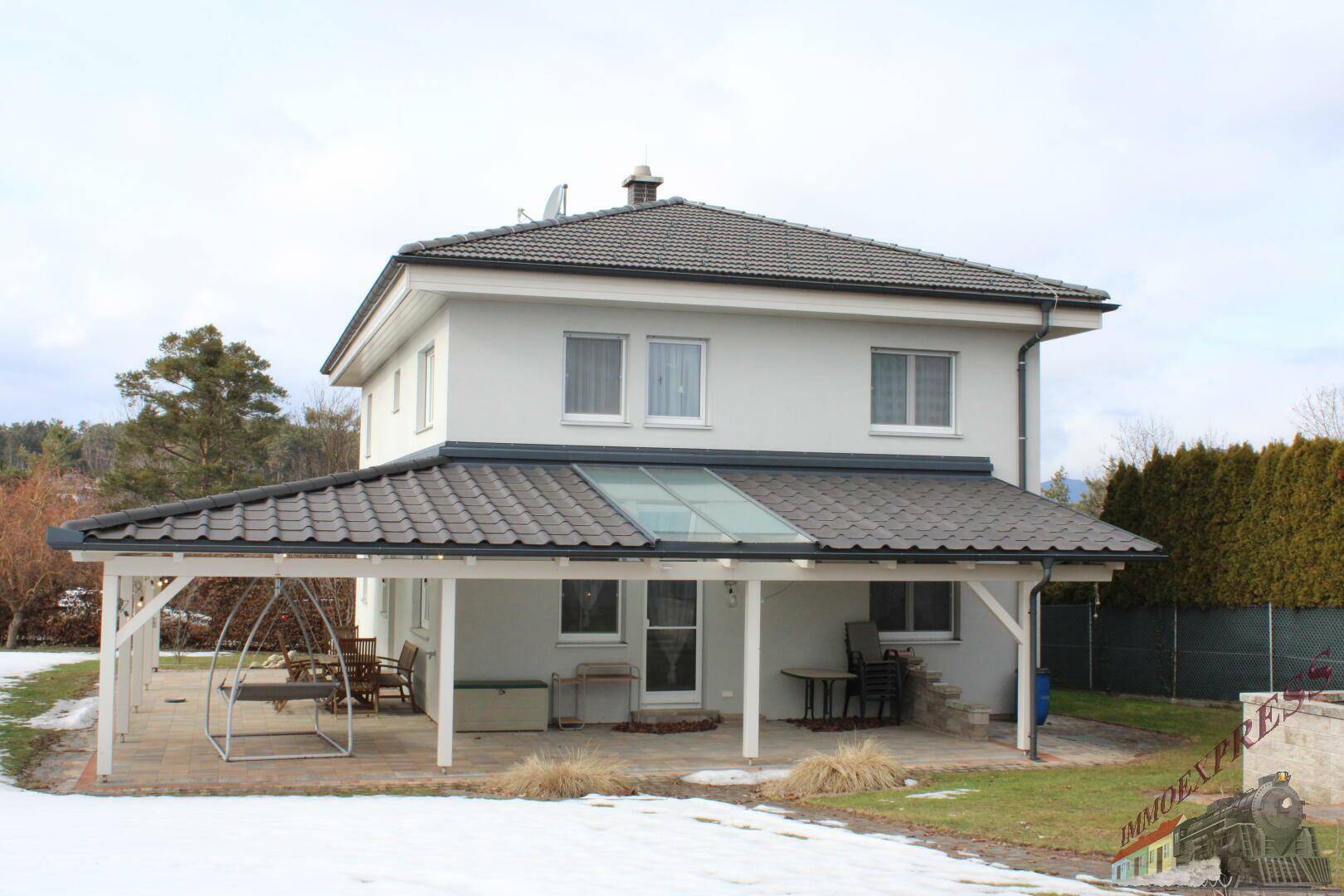 Rückansicht des Hauses mit überdachter Terrasse und Gartenmöbeln.