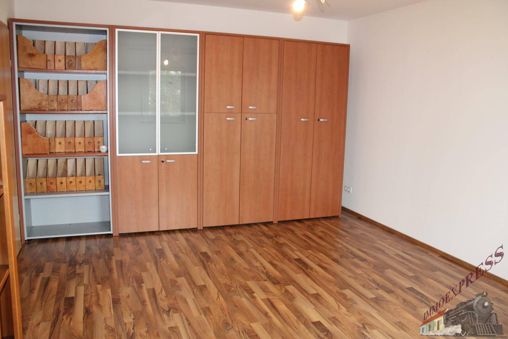 Schlafzimmer mit Laminatboden und einer Wand voller Einbauschränke.