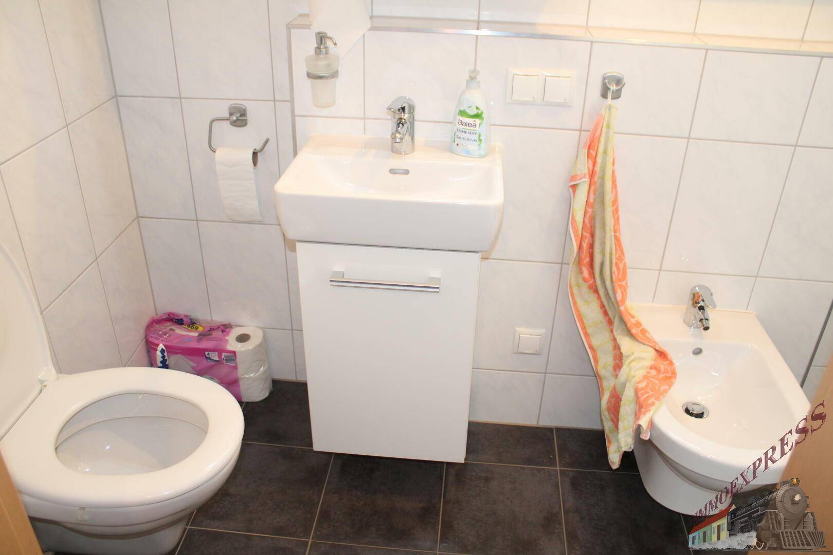 Kleine Gästetoilette mit Waschbecken, WC und Bidet.