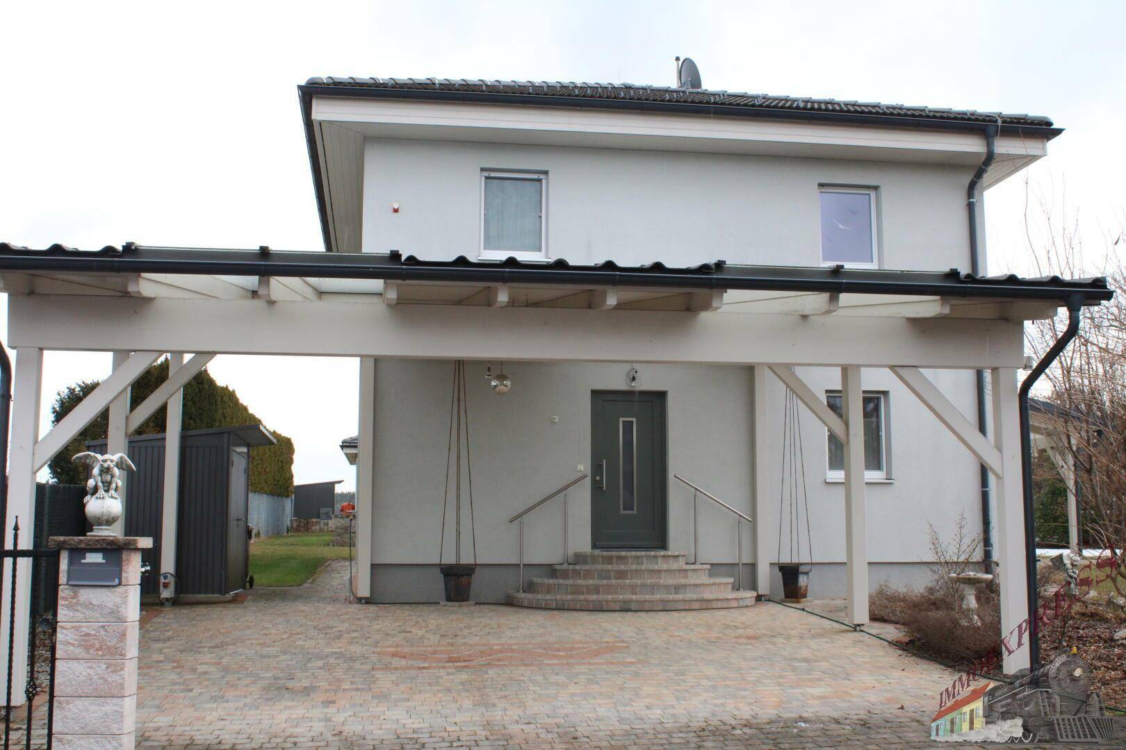 Eingangsbereich des Hauses mit Carport und gepflastertem Zugang.
