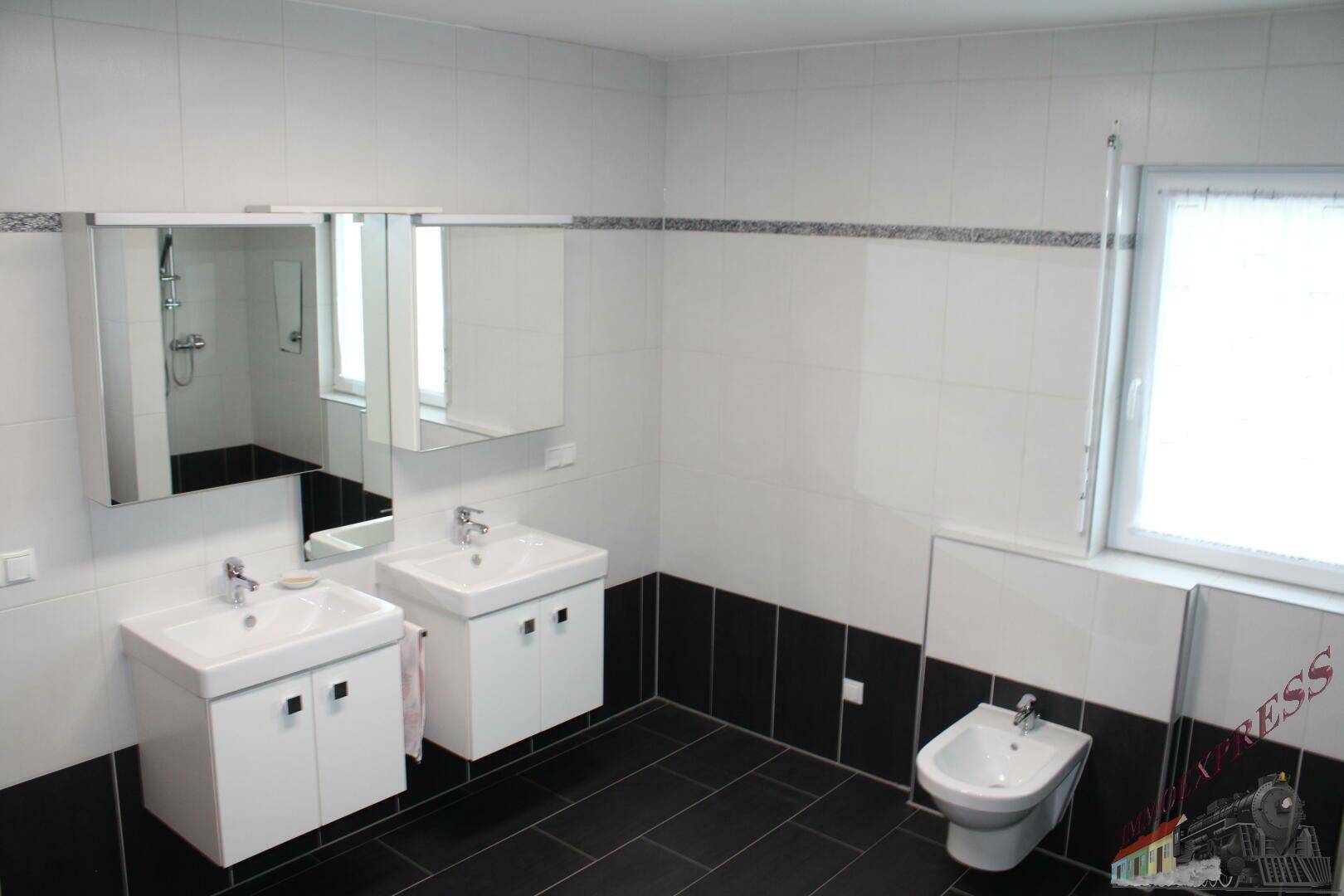 Modernes Badezimmer mit Doppelwaschbecken, Bidet und Fenster.