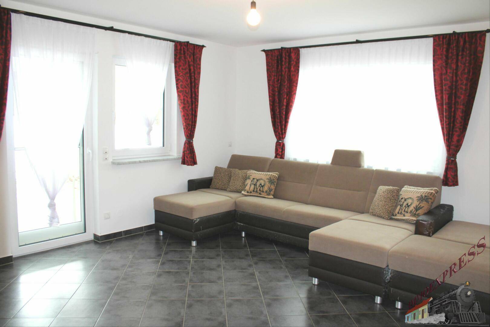 Helles Wohnzimmer mit großem Ecksofa und Zugang zum Außenbereich.