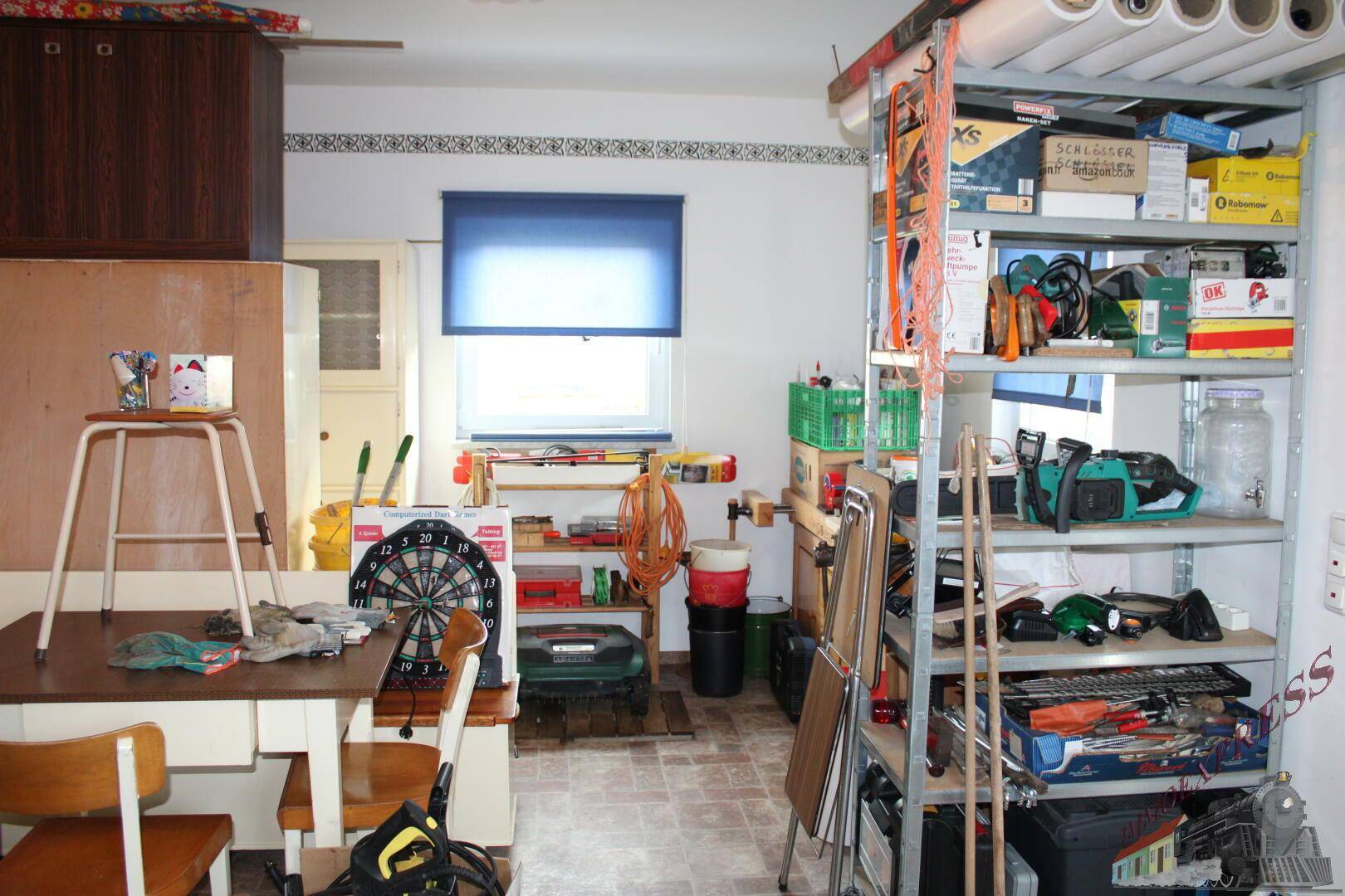 Geräumiger Hauswirtschaftsraum mit Regalen, Werkzeugen und Arbeitsbereich.