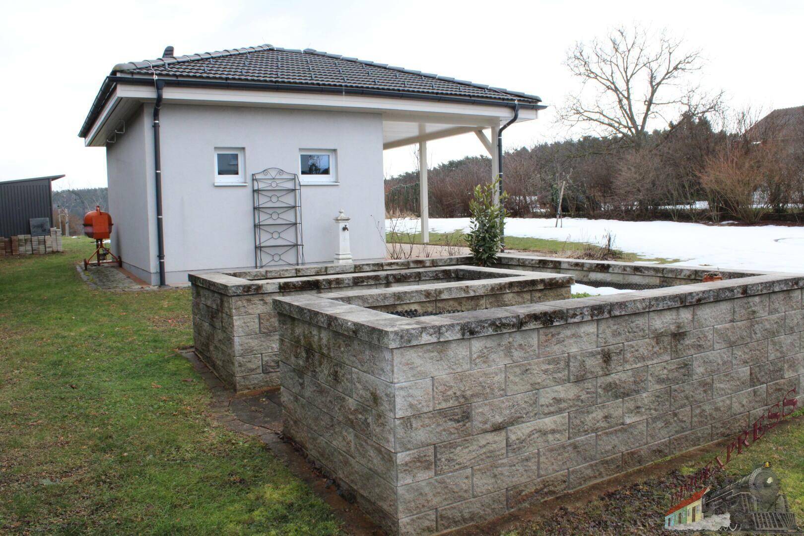 Gartenbereich mit Hochbeeten und einem kleinen Nebengebäude.