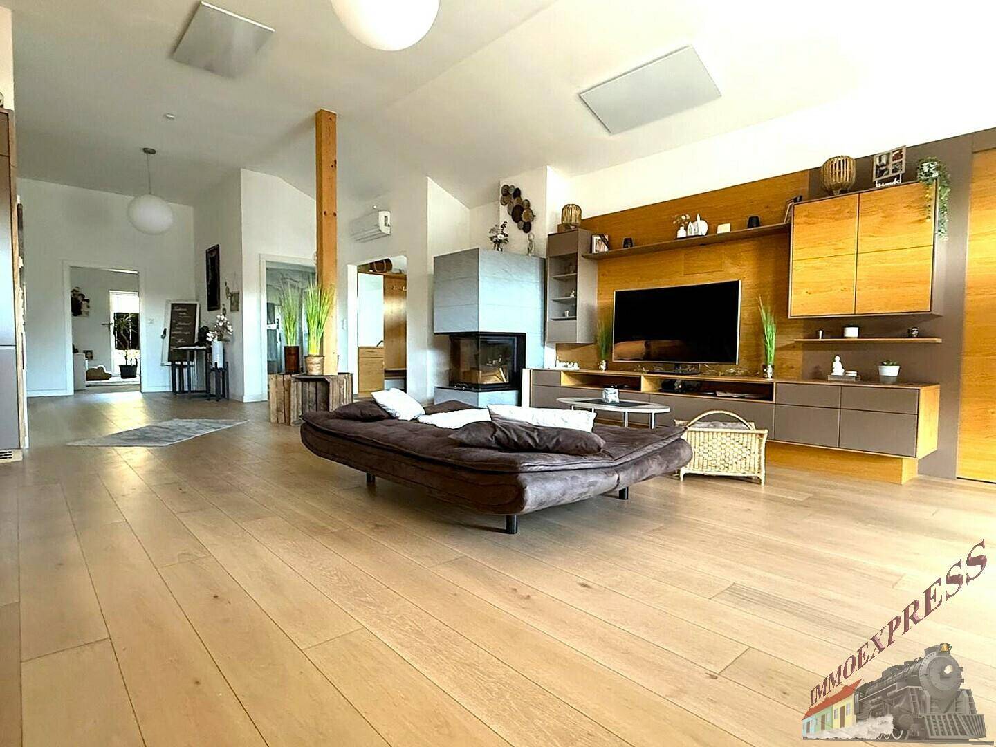 Geräumiges Wohnzimmer mit Holzboden, modernem Kamin und stilvoller Einrichtung.