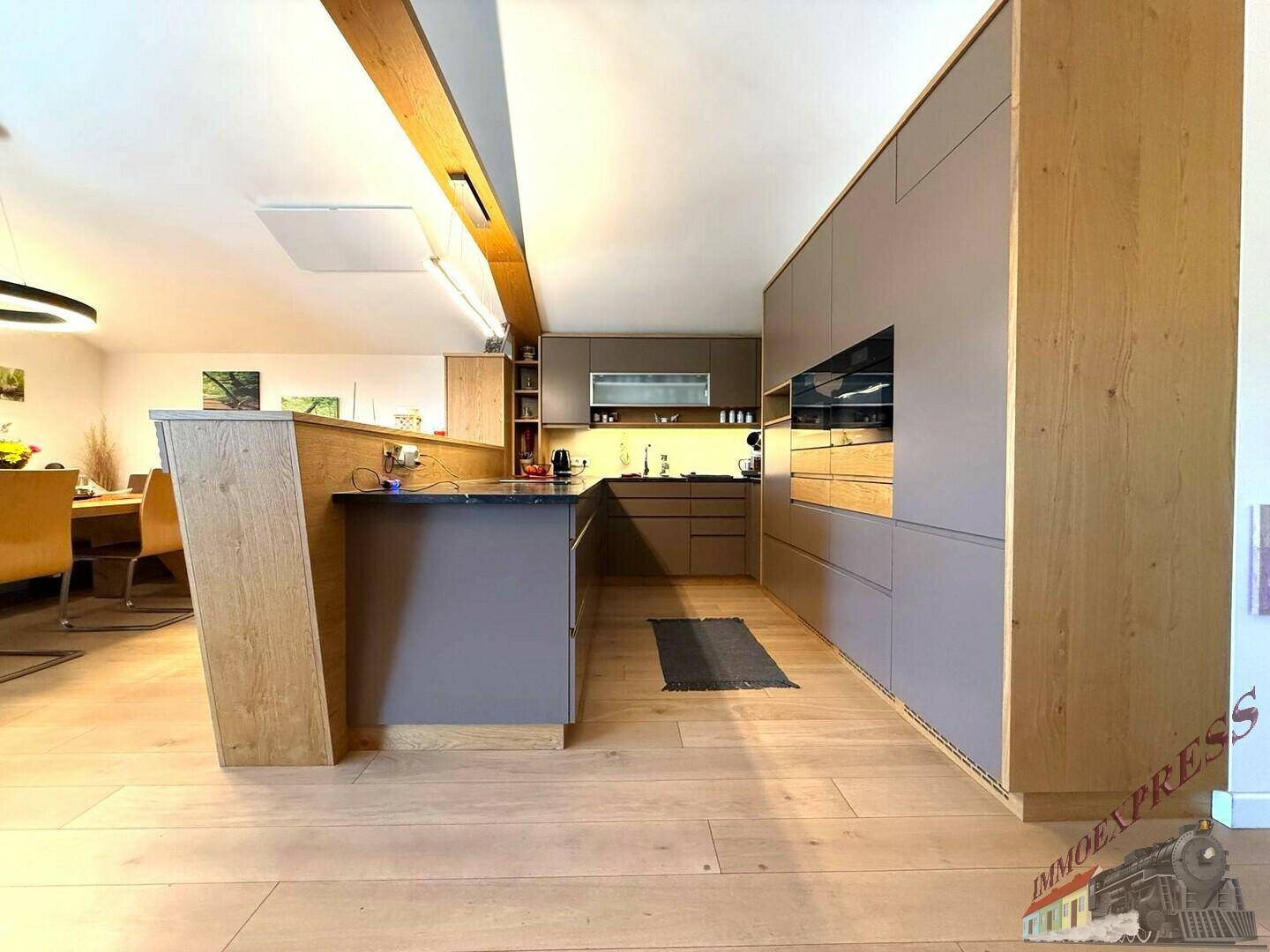 Moderne Küche mit Holz- und Grautönen, Kücheninsel und hochwertigen Einbaugeräten.