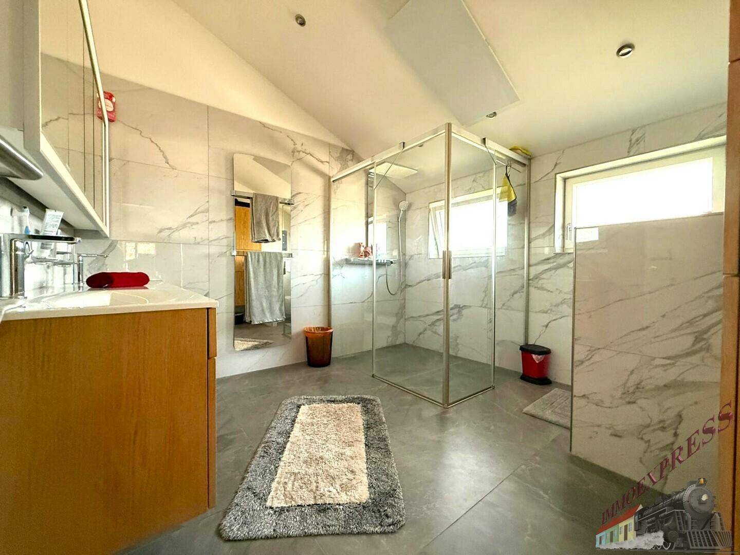 Helles Badezimmer mit begehbarer Dusche, Doppelwaschbecken und eleganten Marmorfliesen.